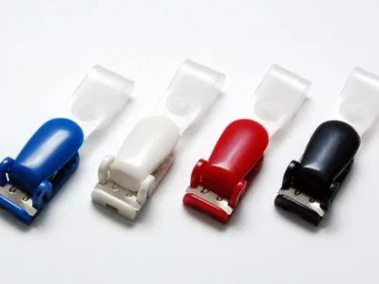 Cuatro pinzas de plástico tipo cocodrilo en azul, blanco, rojo y negro