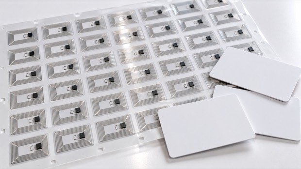 Ilustración de un pliego de antenas NFC con chip junto a tres tarjetas de PVC en blanco